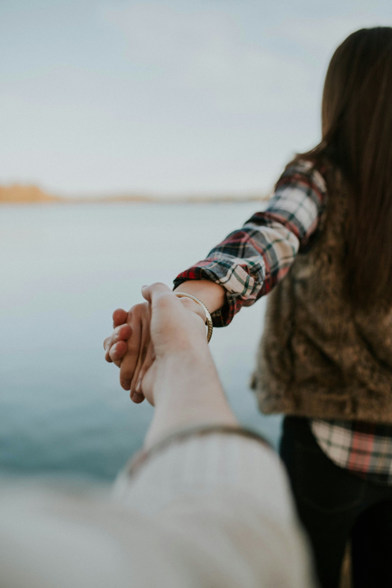 Person holding a date's hand near water before meeting in public